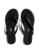 Black minimalist leather flip-flops featuring thin straps, a thin sole, and subtle gold branding on the footbed.