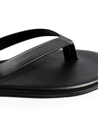 Simple black leather thong sandal with smooth, wide straps and a flat, minimalist sole.