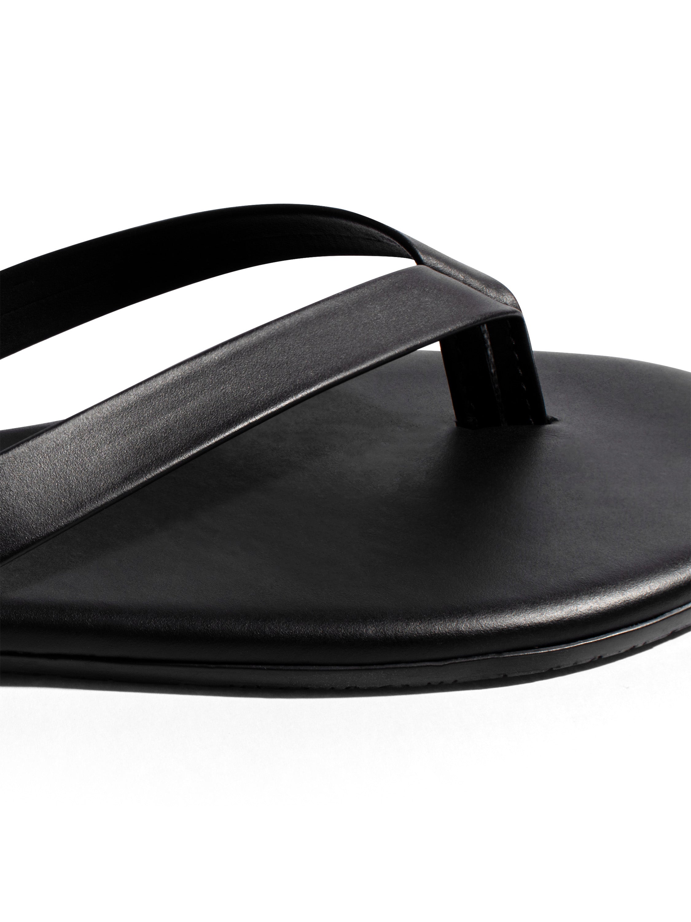 Simple black leather thong sandal with smooth, wide straps and a flat, minimalist sole.
