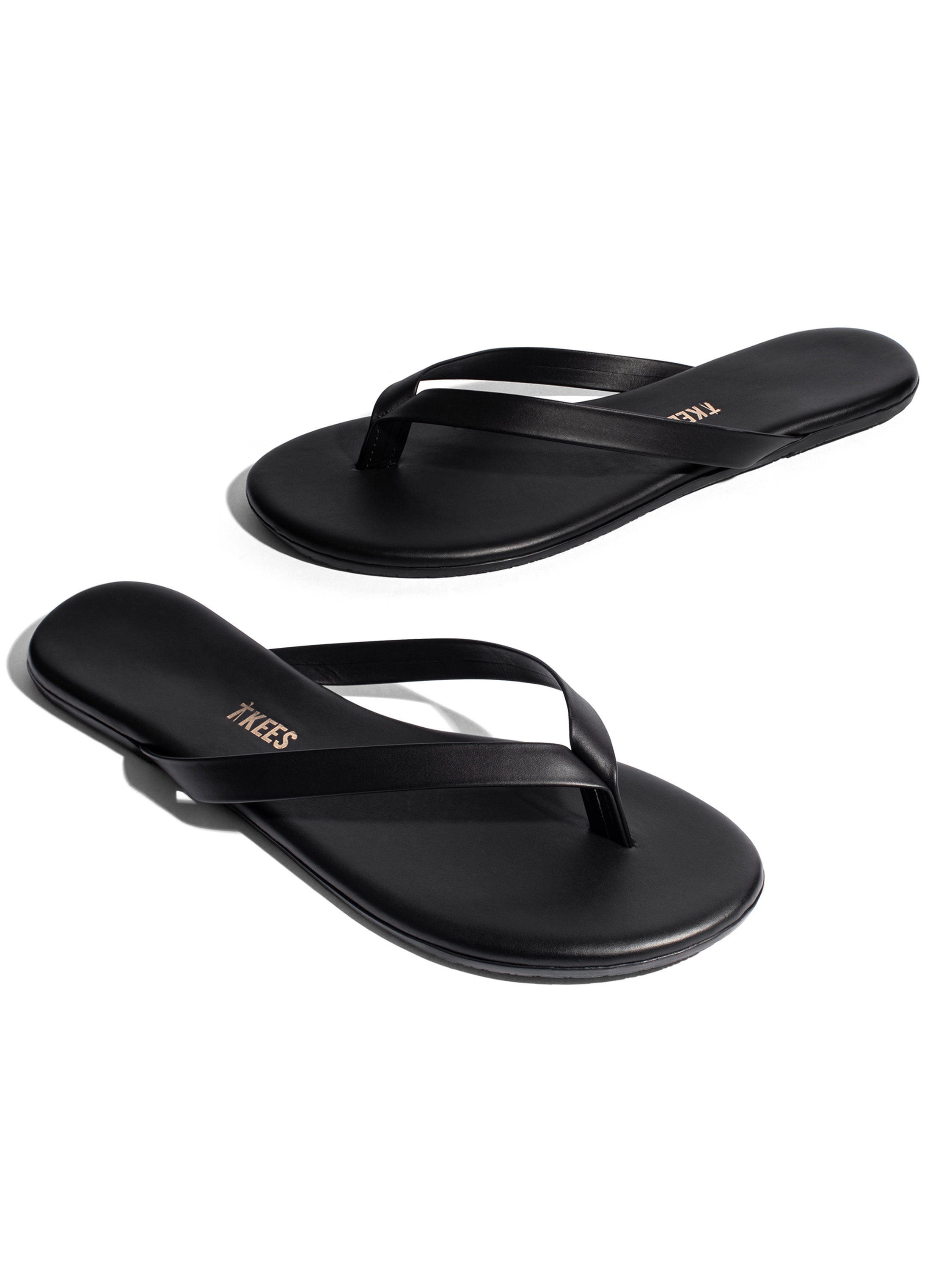 Sleek black leather flat flip-flops featuring thin straps and a minimalist design.
