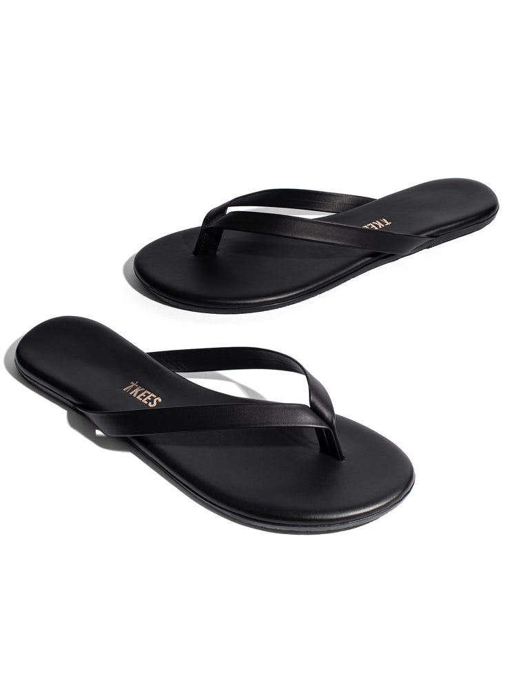 Sleek black leather flat flip-flops featuring thin straps and a minimalist design.