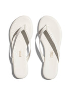 A pair of off-white leather flip-flops with thin straps and a flat sole exhibits a simple, minimalist design.