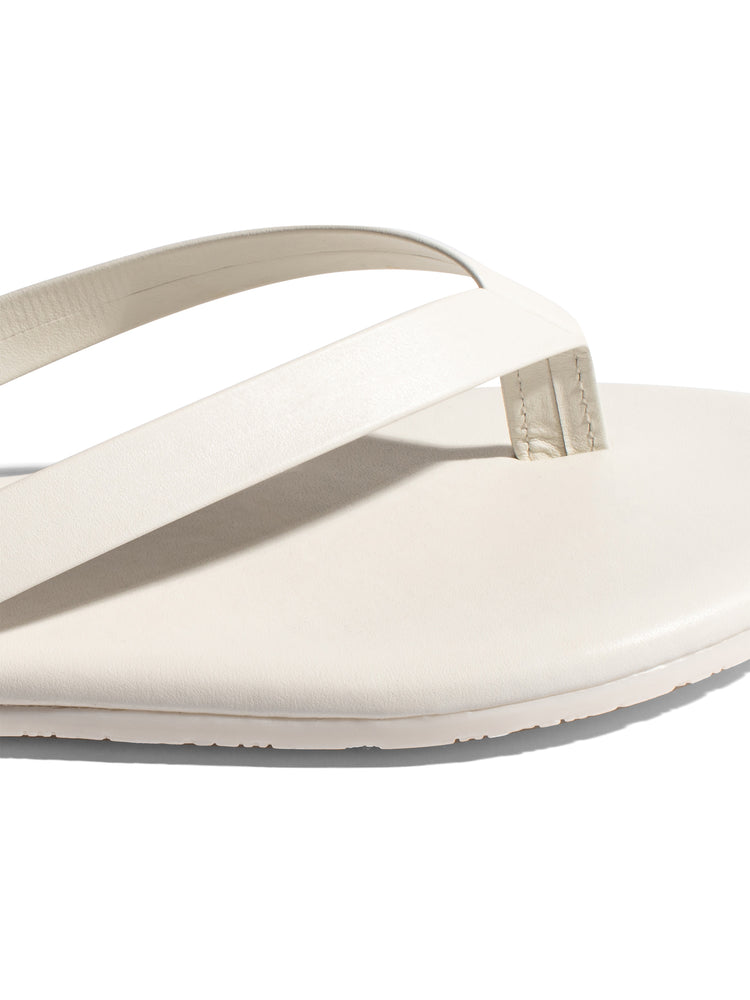 Minimalist off-white leather flip-flop featuring a flat sole and streamlined straps for a modern, casual look.