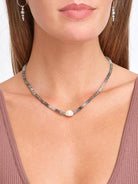 Beaded necklace with grey and pale blue stones, silver spacers, and a central white irregular pearl.