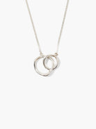 Silver-toned necklace with two interlocking loops, one irregular and one round, on a delicate link chain.