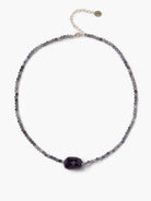 Iolite beaded necklace with small faceted purplish-gray beads, a larger dark purple center bead, and a silver clasp.