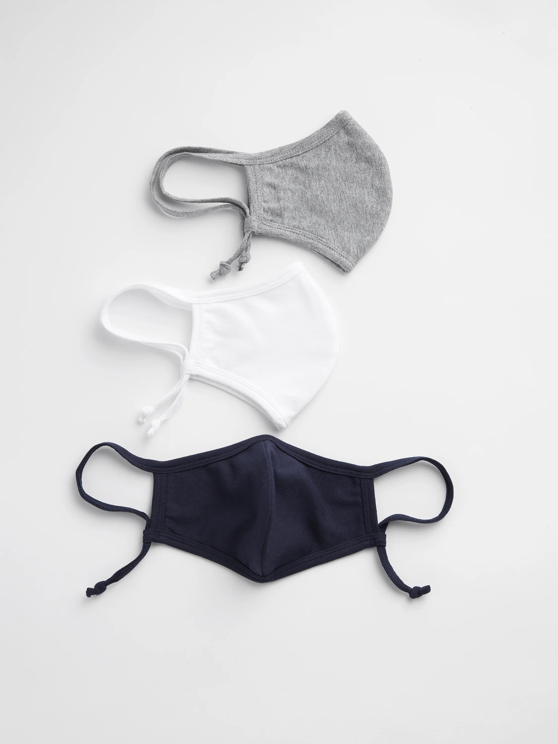 Three cloth face masks: gray, white, and navy blue. Each has ear loops and ties.