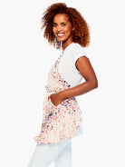 Light wrap apron with a V-neck, tie waist, and pockets. Features a pattern of peach, coral, orange, and black leaf shapes.