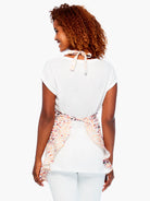 Apron: Light background, abstract peach, orange, brown, and reddish-purple organic pattern. Tied at neck and waist.