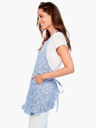 Blue apron with a white and black patterned design, ruffle hem, and pockets.  Adjustable ties.