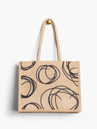 Beige jute tote bag with black swirling circle pattern.  Two beige handles.