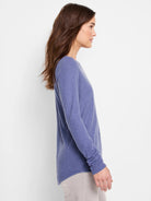 Side profile of a periwinkle blue, long-sleeve shirttail tee.  The shirt has a curved hem.