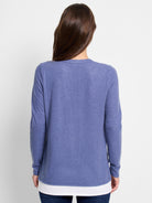 Back view of a periwinkle blue, long-sleeved layered top.  The top layer is blue, the bottom white.