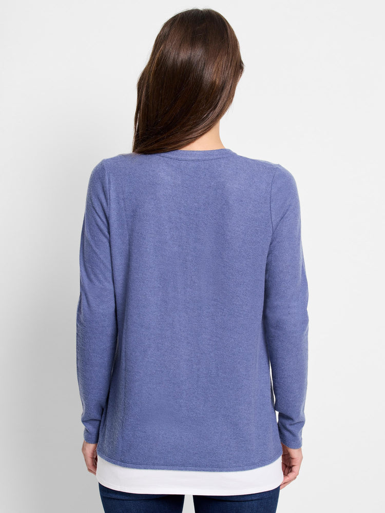 Back view of a periwinkle blue, long-sleeved layered top.  The top layer is blue, the bottom white.