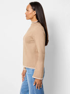 Beige mock-neck top with long sleeves and light beige trim.  Profile view.
