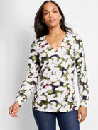 Long-sleeve v-neck top.  Off-white background with blurred olive green, dark purple, and pink petal-like pattern.