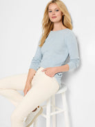 Light blue long-sleeved boatneck shirt.  Model wears off-white pants and white shoes.