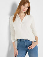 Cream long-sleeve ribbed polo top with collar and open V-neck.