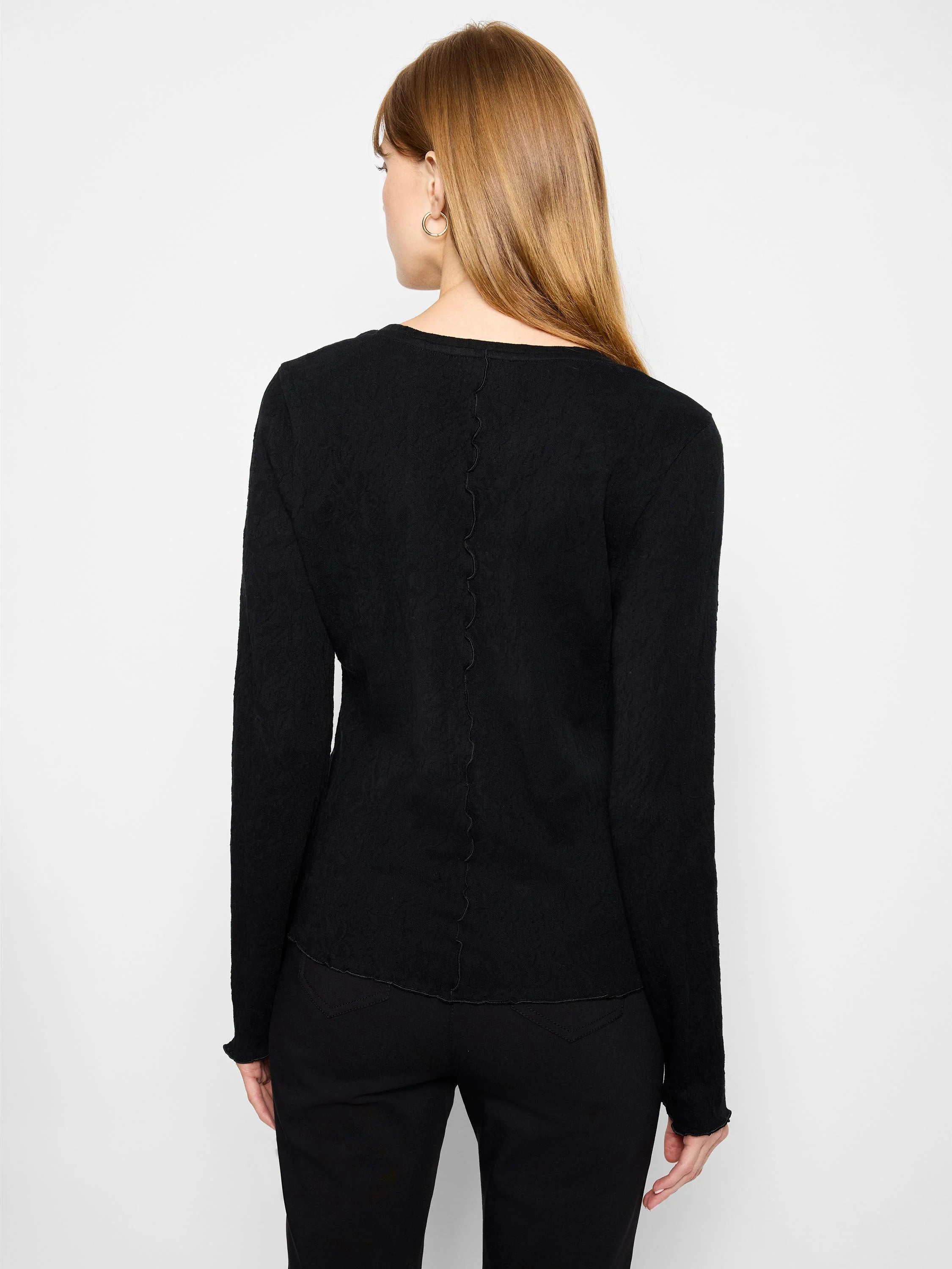 Black V-neck knit shirt with long sleeves and scalloped edges.  Textured fabric.