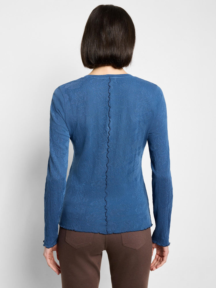 Blue textured knit V-neck long-sleeve shirt; scalloped hem and cuffs.  Back view.