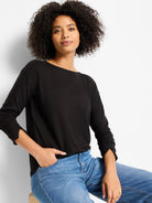Black long-sleeved top with a wide neckline and unique slit cuffs, shown on a woman.