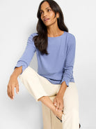 Soft blue knit long-sleeve top with a boat neck and relaxed fit.