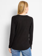 Black long-sleeved top with white underlayer visible at round neck, and a curved hem.