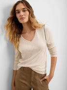 Light cream long sleeve V-neck tee with dark piping on shoulders and sides.