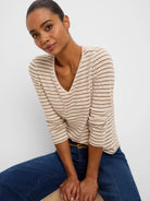 Cream v-neck long sleeve tee with narrow horizontal brown stripes.