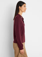 Burgundy knit tee with subtle puff sleeves, polo collar, and metal snap buttons. Worn by a model.