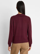 Burgundy knit puff sleeve tee with a collar, seen from behind on a model wearing brown pants.