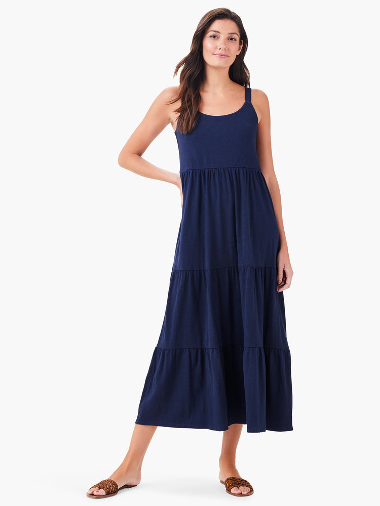 Navy blue tiered maxi dress, sleeveless, with a scoop neck.  The model is wearing brown sandals.