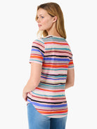 Short-sleeve V-neck tee.  Multicolored horizontal stripes on a light pink background.  Includes orange, blue, teal, and...