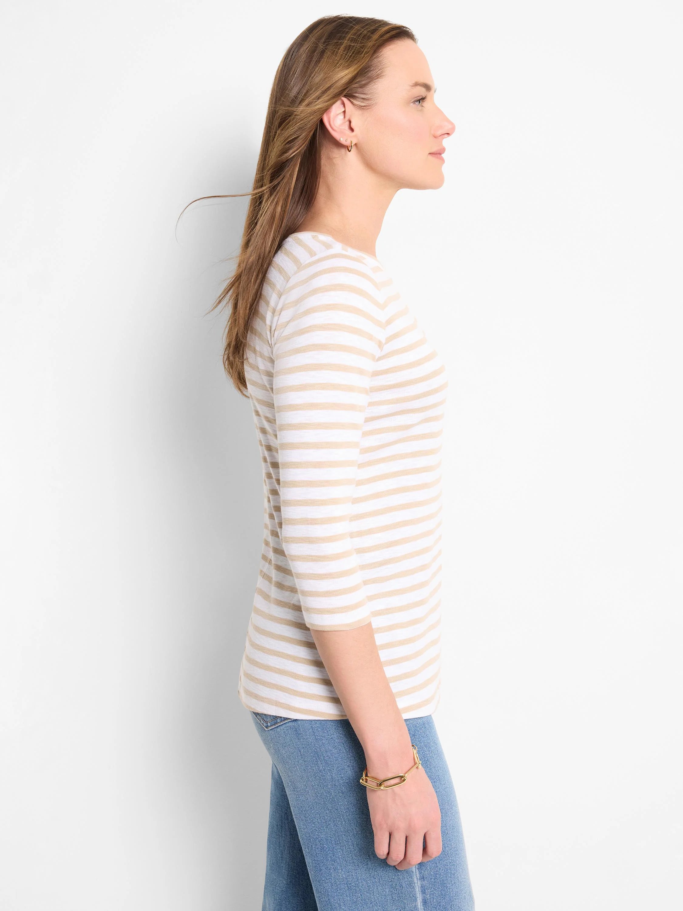 Woman wearing a white and tan striped 3/4 sleeve boat neck tee.