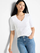 White v-neck, short-sleeve shirt with gold buttons on shoulders.