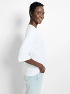 White 3/4 sleeve t-shirt with frayed neckline and sleeve edges.