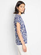 Image of a short-sleeved, crew-neck tee.  Off-white background with a navy blue abstract print.