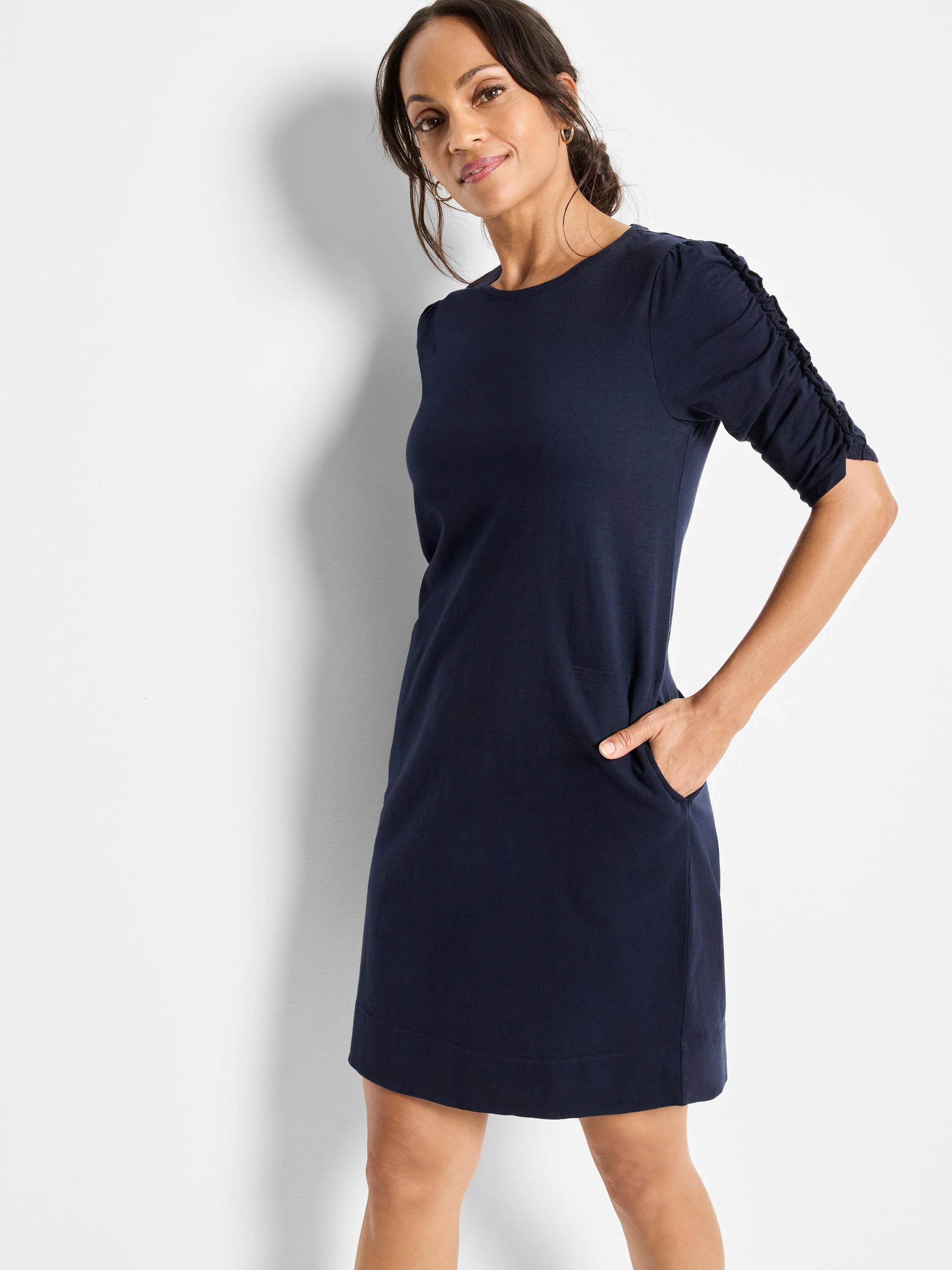 Navy blue, elbow-sleeve dress with ruched detailing on the sleeves and a simple, straight hemline.  It has pockets.
