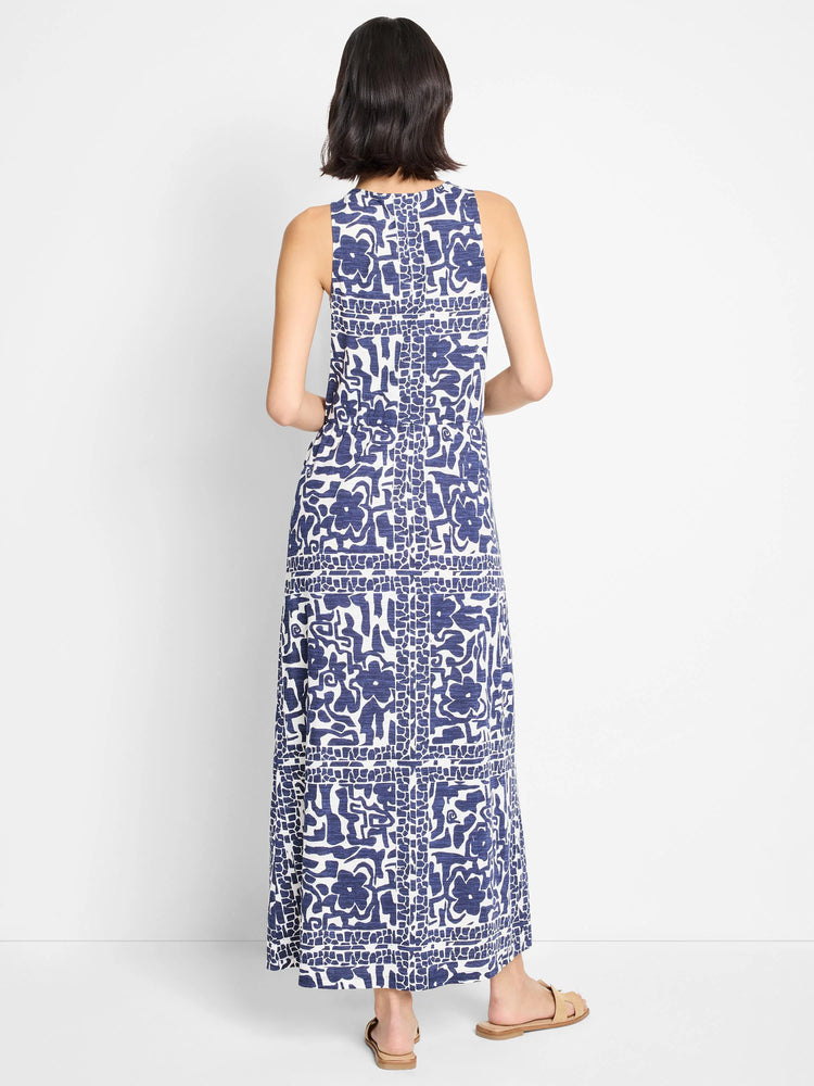 Back view of sleeveless maxi dress.  Off-white background with navy blue abstract floral and geometric print.