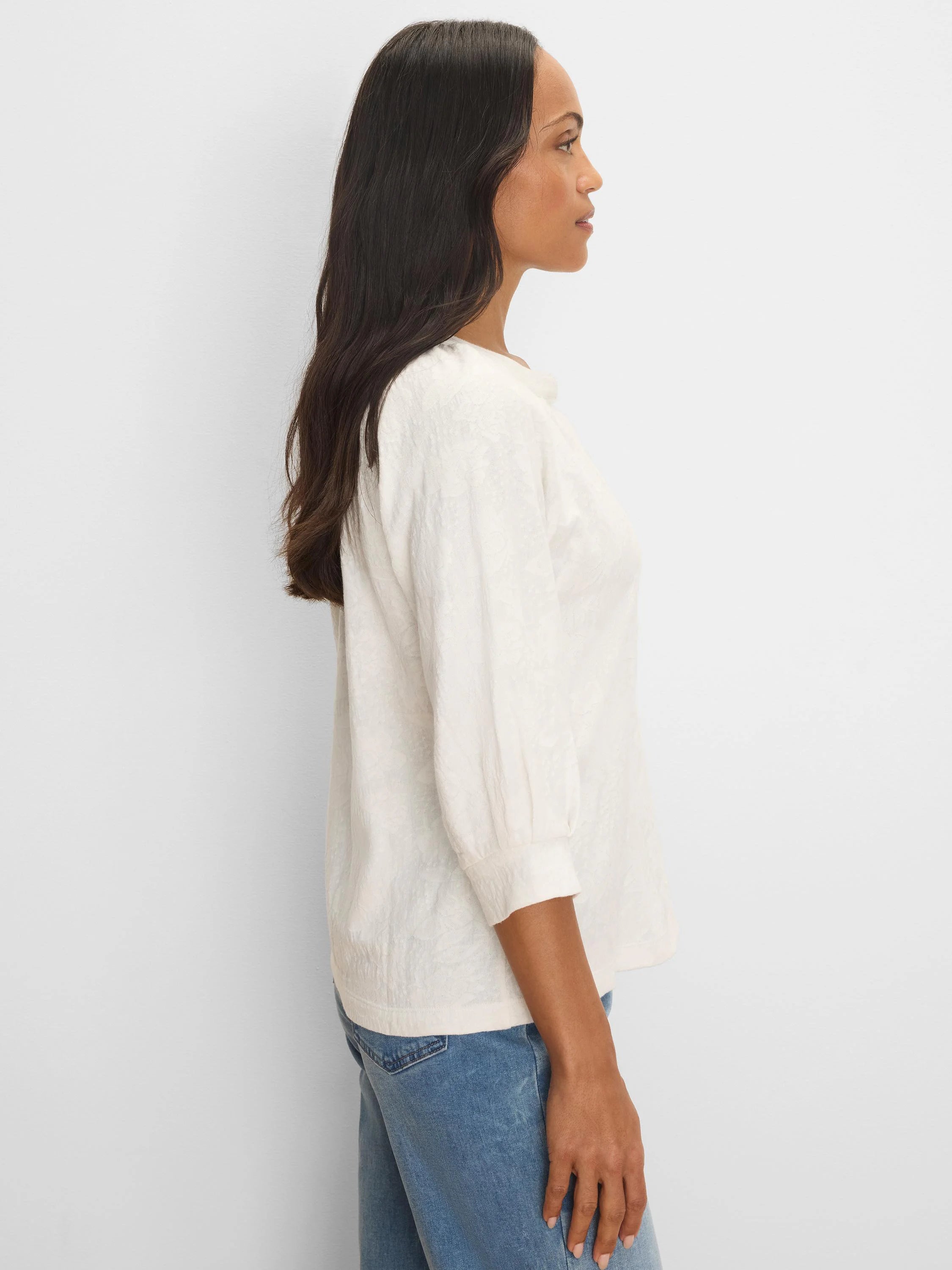 Cream-colored knit top with subtle pattern, relaxed fit, and 3/4 length sleeves with gathered cuffs. Model shown from side.