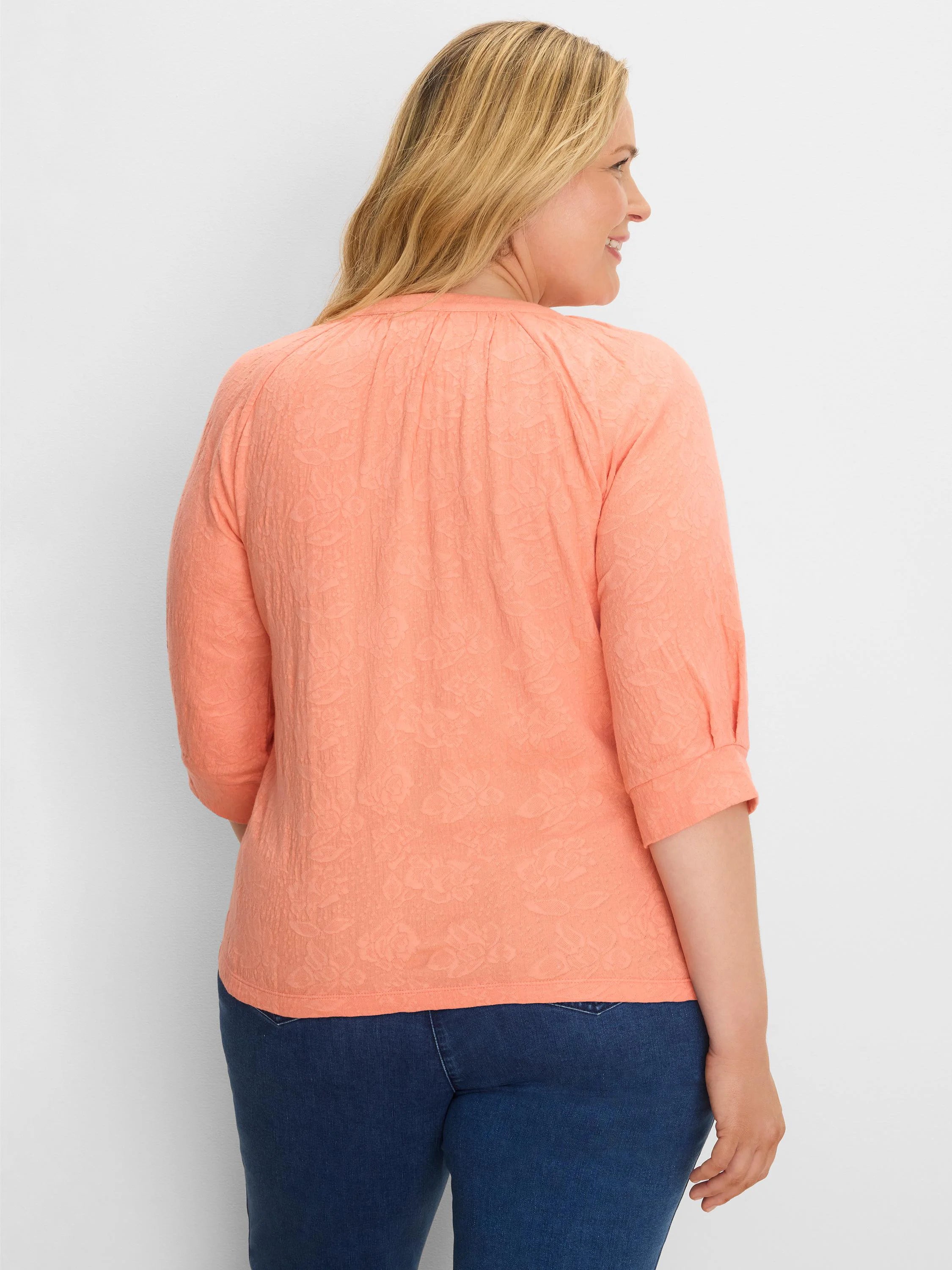 Peach lace knit top with a subtle floral pattern, featuring 3/4 cuffed sleeves. Model is shown from the back.