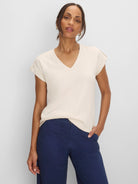 Light cream V-neck tee with subtle geometric lace knit texture and rolled cap sleeves.