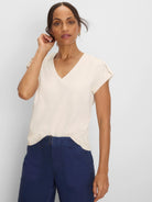 Cream V-neck tee with cap sleeves and a subtle lace knit texture.