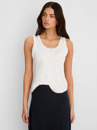 Off-white cotton slub tank top with ruffled neckline and curved hem.