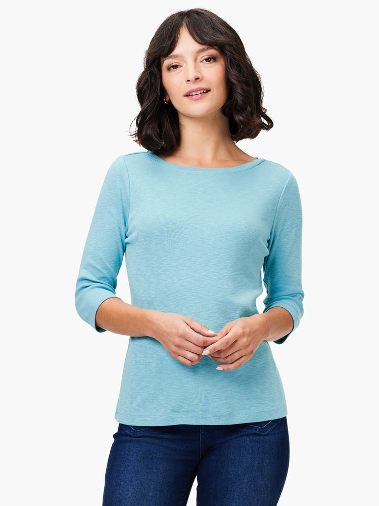 Woman wearing a light blue textured 3/4 sleeve boat neck tee.