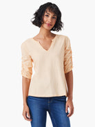 Peach-colored, elbow-length ruched sleeves, split v-neck.