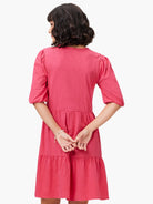 Pink tiered V-neck dress with short, puffed sleeves.  Back view.