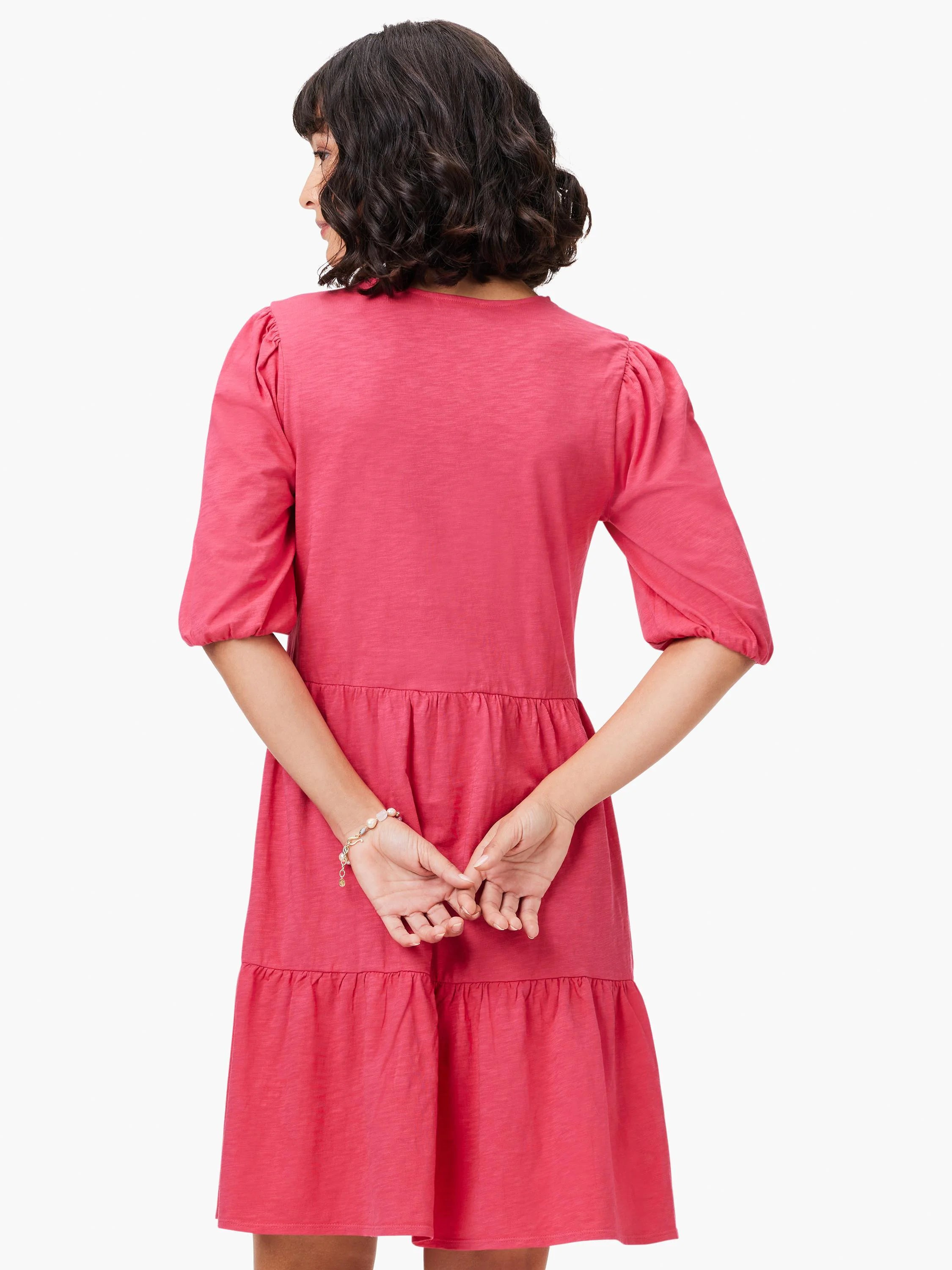 Pink tiered V-neck dress with short, puffed sleeves.  Back view.