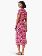 Pink midi dress with dark purple and orange abstract print, short sleeves, and side slit.
