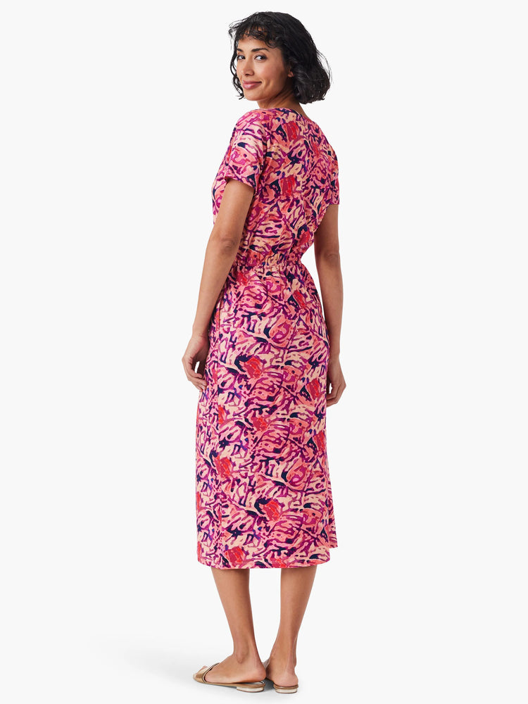 Pink midi dress with dark purple and orange abstract print, short sleeves, and side slit.